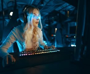 Blonde in cyberpunk glasses plays computer games, fascinated by technology and the virtual world.